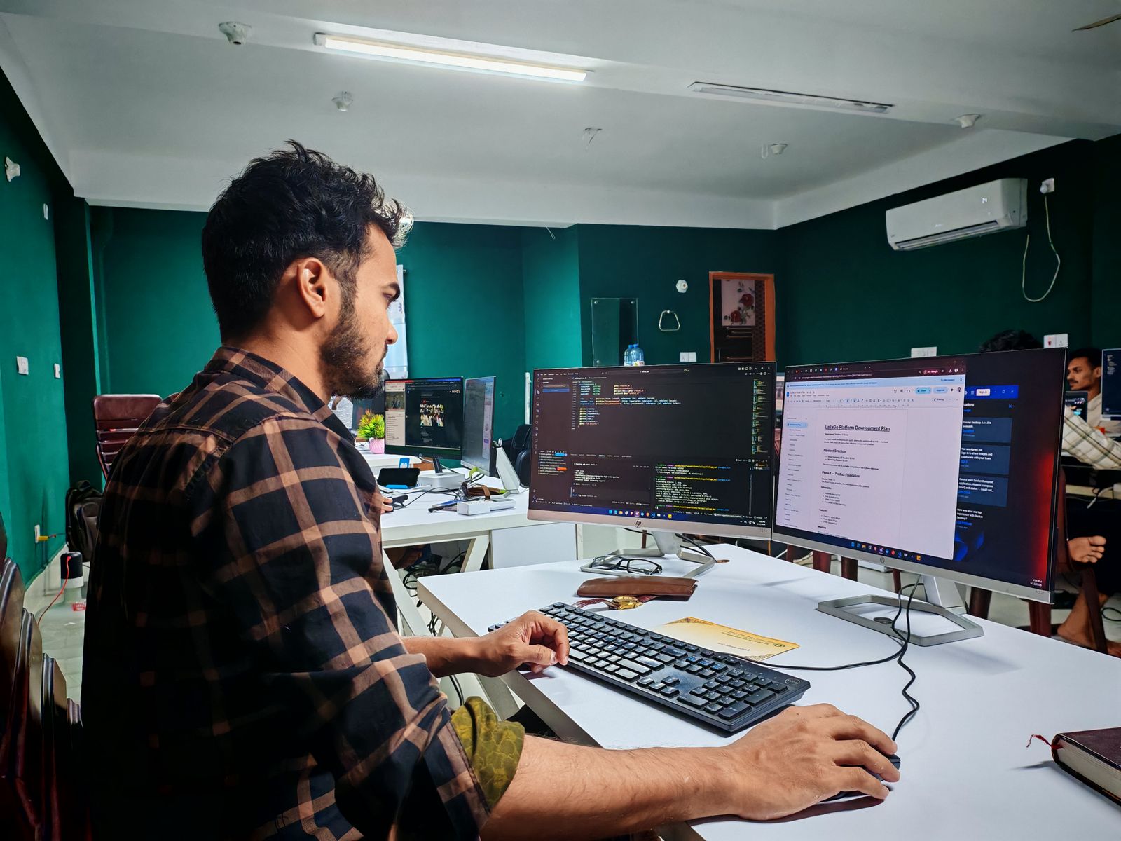 A developer working on code across two monitors