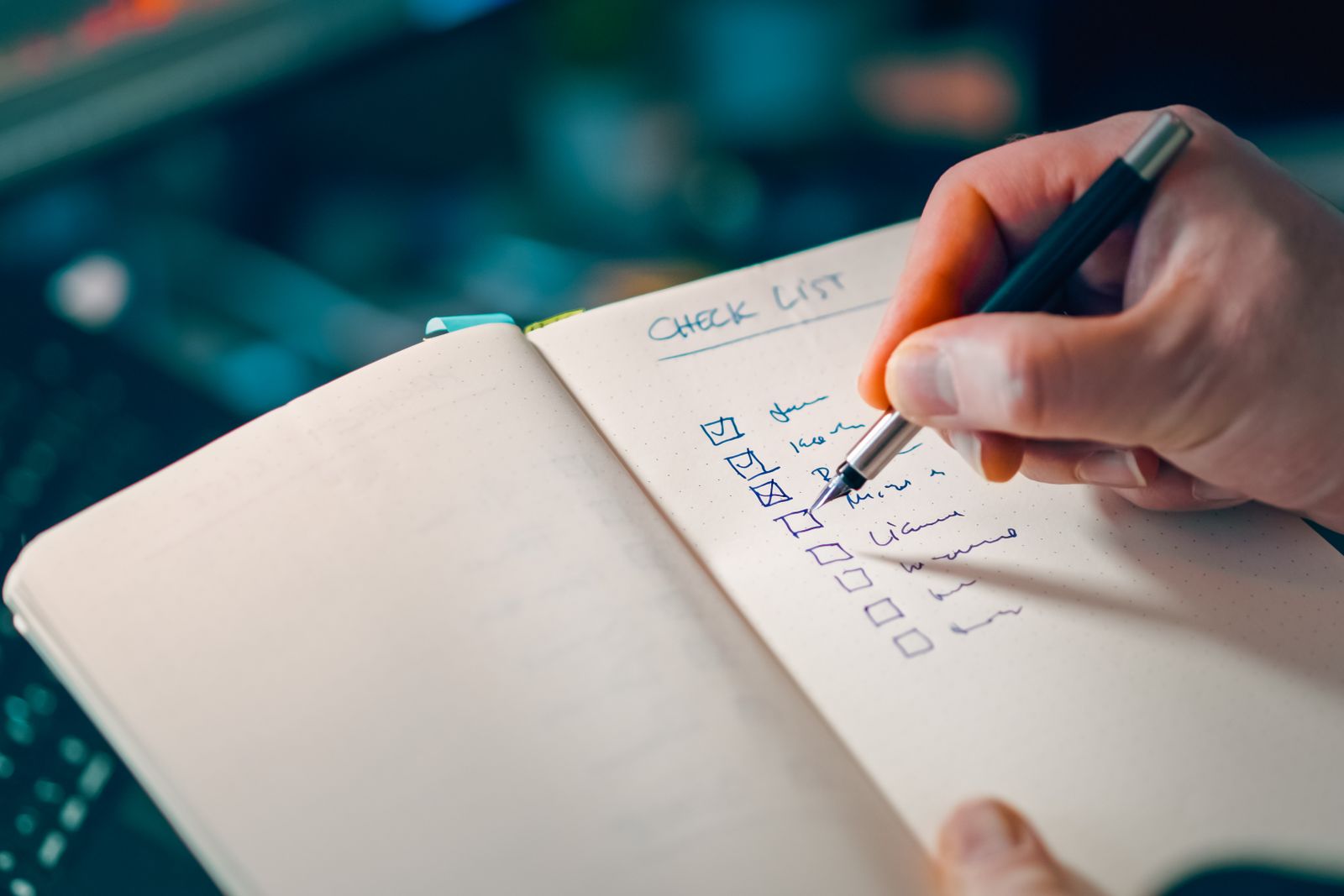 A hand writing a checklist in a notebook